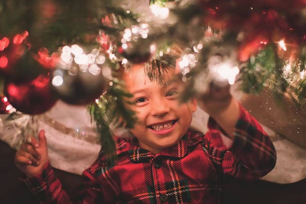 Boy hanging looking at camera under the Christmas Tree at night time San Diego, CA, United States CR_CHDO200731B-464558-01 ,model released, Symbolfoto