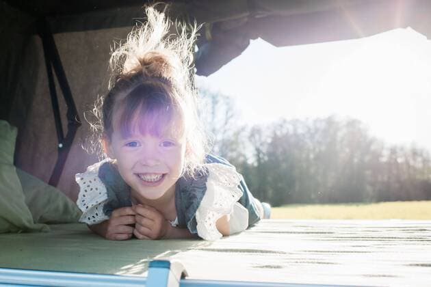 portrait of a young girl sat in a roof top tent smiling at sunset Norrtälje, Stockholm County, Sweden CR_RABE200627-418710-01 ,model released, Symbolfoto