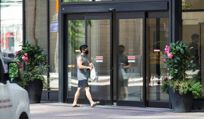 (200805) -- TORONTO, Aug. 5, 2020 -- A man wearing a face mask walks to a condo building in Toronto, Canada, on Aug. 5, 2020. Starting on Wednesday, the City of Toronto required building owners or operators to have a mandatory masking policy in place for enclosed common spaces like lobbies, elevators and laundry rooms. (Photo by Xinhua) CANADA-TORONTO-COVID-19-MEASURES ZouxZheng 