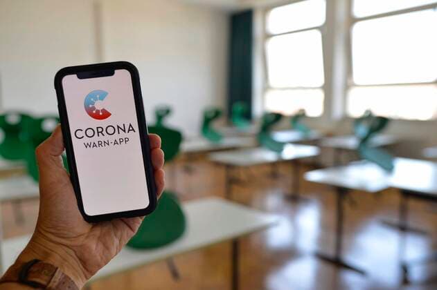 Hand holds smartphone with Corona Warn App in the classroom, Corona crisis, Germany, Europe Copyright: imageBROKER/MichaelxWeber iblimw05825448.jpg