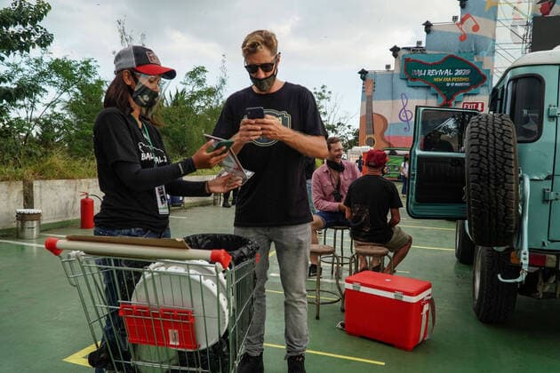 August 17, 2020, Gianyar, Bali, Indonesia: Organizer worker sell foods and beverages using e-money transaction. First drive-in music concert in Bali held in Ubud region amid Covid-19 coronavirus outbreak to encourage Bali musicians to keep productive and having health mentality after 5 months pandemic period. The spectators sllowed to be outside the car which still inside each boundary line. Gianyar Indonesia - ZUMAb245 20200817_zip_b245_036 Copyright: xDickyxBisinglasix