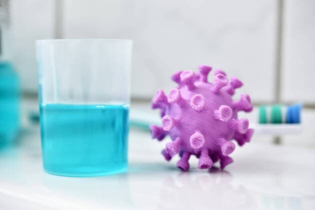 Coronavirus miniature next to a cup with mouthwash ** NUR FUER REDAKTIONELLE ZWECKE ** EDITORIAL USE ONLY **