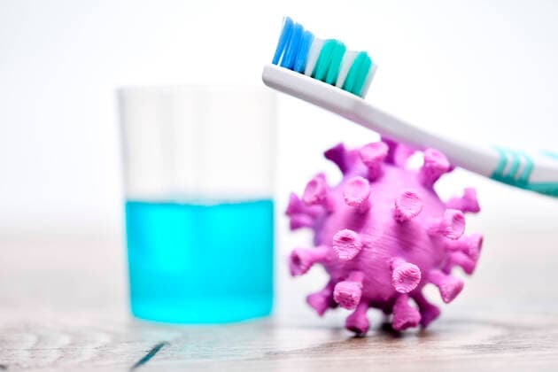 PHOTOMONTAGE, Coronavirus miniature next to a cup with mouthwash ** NUR FUER REDAKTIONELLE ZWECKE ** EDITORIAL USE ONLY **