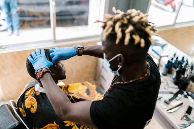 IMAGO Creative: Neue Aussichten Hairdresser with locs cutting male customer s hair in barber shop model released Symbolfoto property released EGAF00570