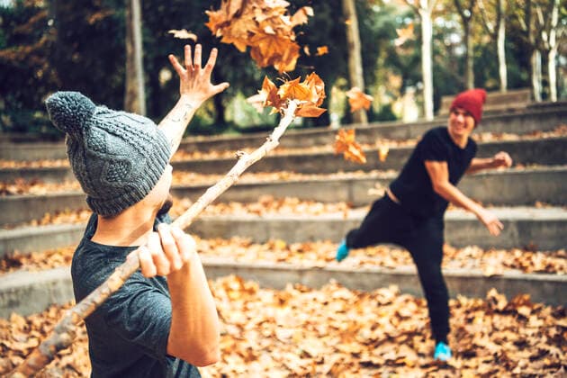 Young male friends playing with autumn leaves in public park model released Symbolfoto property released EHF00755