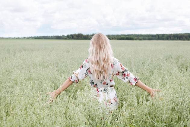 IMAGO Nature: Unsere Erde, Klimawandel, Ernährung, Pflanzen der Zukunft, Hafer Young woman with blond hair standing amidst oats field against cloudy sky model released Symbolfoto EYAF01247