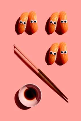 Studio shot of chopsticks, bowl of soy sauce and salmon nigirizushi pieces with googly eyes GEMF03928