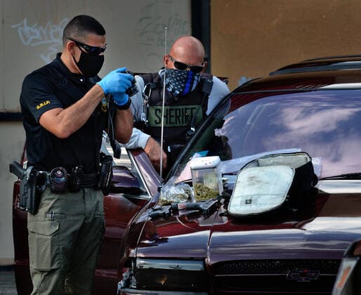 August 29, 2020, Albuquerque, NM, USA: BCSO officers record all the evidence of guns, cash and drugs on the hood of a vehicle they stoped at Pennsylvania and Central NE. Saturday, Aug. 29, 2020. Albuquerque USA - ZUMAab1_ 20200829_zaf_ab1_004 Copyright: xJimxThompsonx
