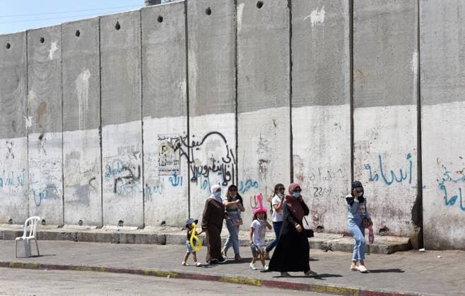 Palestinians walk beside the Israeli separation wall in Shurafat Refugee Camp near Jerusalem, on Monday, August 31, 2020. Senior U.S. Presidential Advisor Jared Kushner called on Palestinians to return to the negotiations with Israel and not be stuck in the past upon arrival to the AUE on the first direct flight from Israel to Abu Dhabi.  JER2020083111 DEBBIExHILL