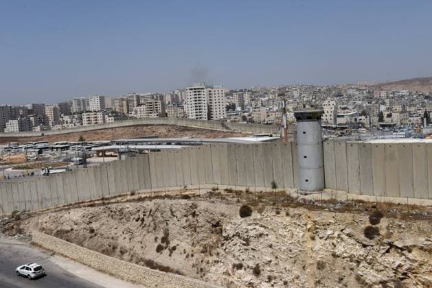 A car drives beside the Israeli separation wall at the Qalandiya Checkpoint, West Bank, on Monday, August 31, 2020. Senior U.S. Presidential Advisor Jared Kushner called on Palestinians to return to the negotiations with Israel and not be stuck in the past upon arrival to the AUE on the first direct flight from Israel to Abu Dhabi.  JER2020083114 DEBBIExHILL