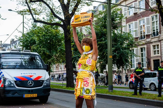 September 1, 2020, The Hague, South Holland, Netherlands: A female XR model posing with her bag close to the Dutch police during the fashion show..An XR fashion show was carried out in front of the House of Representatives in The Hague. Models wore yellow, black, and white colourful second-hand outfits to symbolise the collectivity of bees, to show that thinking and working together can help us out of this crisis. The Hague Netherlands - ZUMAs197 20200901_zaa_s197_019 Copyright: xAnaxFernandezx