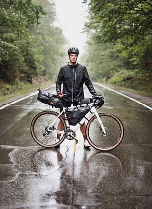 male bike packer stands with bike in road in pouring rain, Maine Boothbay, ME, United States CR_SSNF200905C-492967-01 ,model released, Symbolfoto