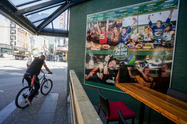 (200910) -- VANCOUVER, Sept. 10, 2020 -- A cyclist passes by a poster on the wall of a bar on Granville street in Vancouver, British Columbia, Canada, Sep 9, 2020. As more evidence found nightclubs and bars are the sources led to the rebound of COVID-19 cases in Vancouver, health authority ordered to close all nightclubs and banquet halls immediately. (Photo by Xinhua) CANADA-VANCOUVER-COVID-19-MEASURE LiangxSen 