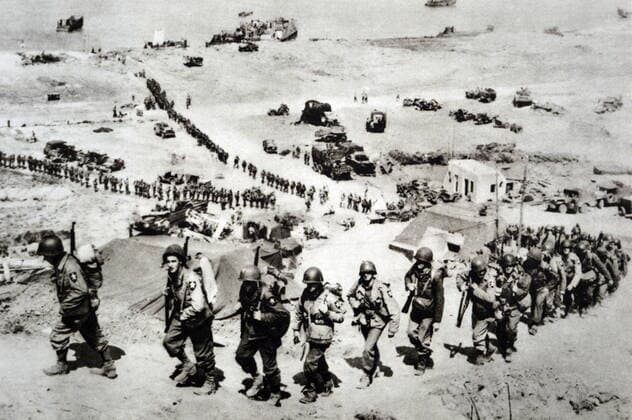 Black and white photograph of World War II (1939-1945) showing American troops landing at Normandy on 6 June 1944; a view from a hill top overlooking the sea and American troops marching up the hill. WorldxHistoryxArchive 917_33_WHA_134_0625