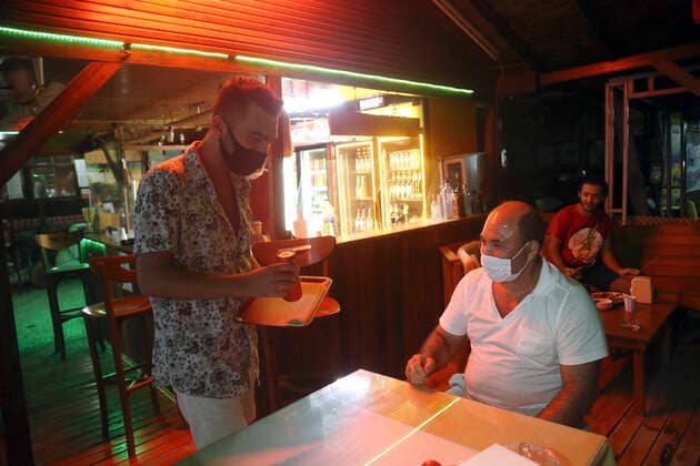 (200915) -- ANTALYA, Sept. 15, 2020 -- A waiter wearing a face mask serves food for a customer at a restaurant in Antalya, Turkey on Sept. 15, 2020. Turkey reported 1,742 new COVID-19 cases on Tuesday, raising the total diagnosed patients to 294,620, the Turkish Health Ministry announced. (Photo by Xinhua) TURKEY-ANTALYA-COVID-19-CASES MustafaxKaya 