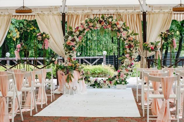 Beautiful wedding set up. Area of the wedding ceremony. Round arch, white chairs decorated with flowers, greenery. Cute, trendy rustic decor. Part of the festive decor, floral arrangement. Copyright: xVITxLEOx