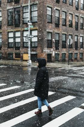 Young woman in warm jacket crossing snowy urban street, New York City, New York, USA  Copyright: TobyxMitchell fStopImages1938030 ,model released, Symbolfoto