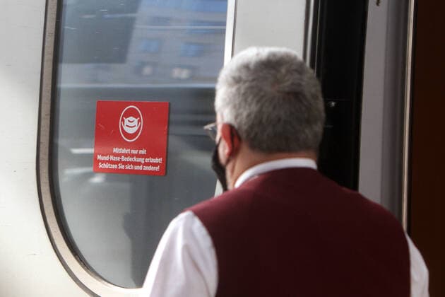Sticker with pictogram Mask obligation and inscription Carriage only with mouth nose Covering allowed on the door of a ready to depart ICE Intercity Express of DB Deutsche n Bahn with a train attendant wearing a mask at Frankfurt Central Station, Hesse, Germany