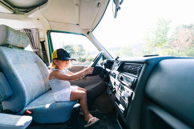 IMAGO Creative: Klimawandel - Nachhaltiges Reisen Girl wearing cap sitting on driver s seat in motor home model released Symbolfoto JCMF01345