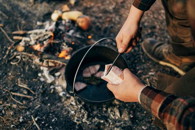 IMAGO Creative: Klimawandel - Nachhaltiges Reisen Bushcrafter cooking in forest model released Symbolfoto SASF00014