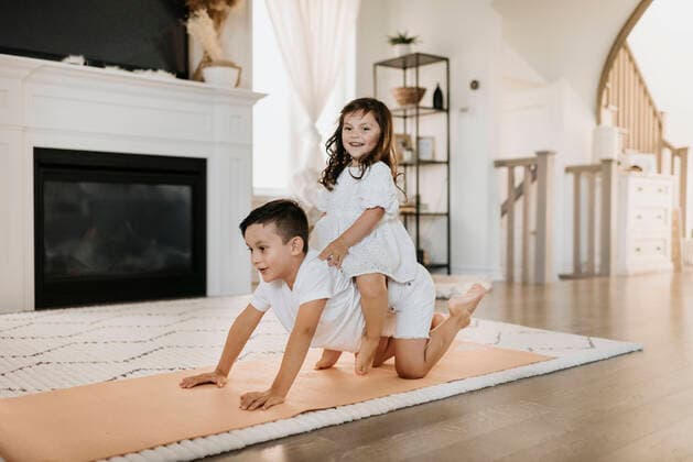 Smiling sister sitting on brother s back in living room model released Symbolfoto property released SMSF00205