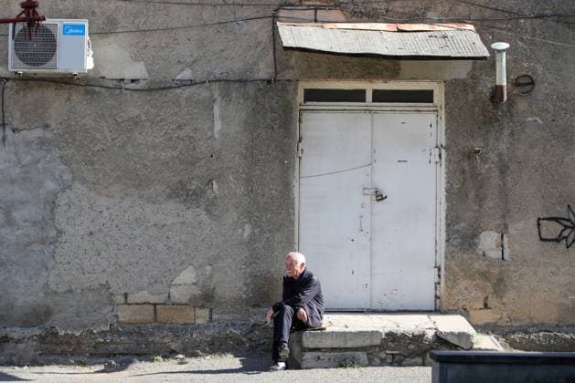 STEPANAKERT, NAGORNO-KARABAKH - OCTOBER 3, 2020: A local resident sits on stairs in a street. The situation in Nagorno-Karabakh escalated on September 27, 2020, with reports from Yerevan on the Azerbaijani troops advancing in the direction of Nagorno-Karabakh and shelling its settlements, including the capital city of Stepanakert. Both Azerbaijan and Armenia have declared martial law and military mobilization, reporting on casualties and injuries among civilians as well. Sergei Bobylev TASS  TS0E98B2