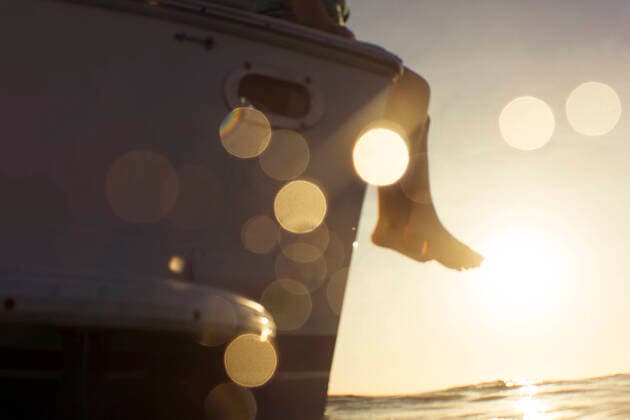 Creative Highlights Symbolfotos Low section of woman sitting on boat in sea during sunset Nassau, New Providence, The Bahamas CR_BRHU200930-502649-01 ,model released, Symbolfoto