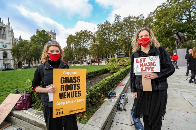 Musicians wearing face protective masks and holding placards are gathered in Parliament Gardens, outside the Houses of Commons in London, on Tuesday, Oct 6, 2020. Musicians in Britain are using their voices and instruments to protest against the government instructions to retrain and lack of support to the industry. , Let Music Live Protest London Parliament Gardens England United Kingdom  , Copyright: xVudixXhymshitix