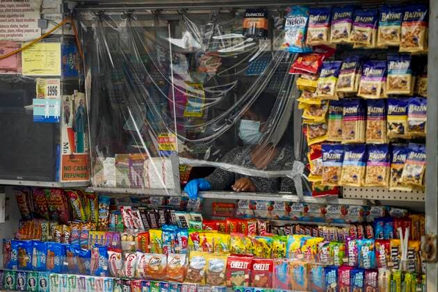 (201008) -- NEW YORK, Oct. 8, 2020 -- A vendor waits for customers behind a plastic covering at her booth at Rego Park of Queens, a COVID-19 hotspot area in New York, the United States, on Oct. 8, 2020. The latest coronavirus positivity rate in the 20 hotspot ZIP codes in Queens, Brooklyn, Orange and Rockland counties in New York State was 5.8 percent, more than five times the statewide positivity rate excluding these ZIP codes which stood at 1.01 percent, tweeted Governor Andrew Cuomo on Thursday. Shutdowns of non-essential businesses, schools and social gatherings in those hotspot areas have gradually taken effect this week under the instructions of the governor and New York City Mayor Bill de Blasio, though it has triggered criticism an