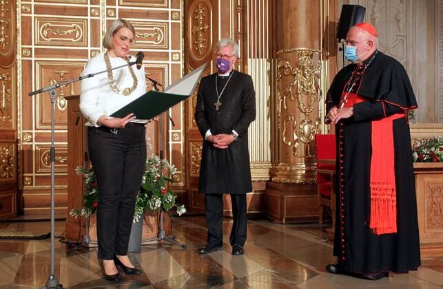 Der Ratsvorsitzender der Evangelischen Kirche in Deutschland (EKD), Heinrich Bedford-Strohm, und der Muenchner Erzbischof Kardinal Reinhard Marx haben den Augsburger Friedenspreis erhalten. (Foto: Oberbuergermeisterin Eva Weber ueberreicht den Friedenspreis an Bedford-Strohm (M.) und Marx) Beim Festakt am Samstagabend (10.10.2020) im Goldenen Saal des Rathauses in Augsburg sagte als Laudator der fruehere Bundespraesident Joachim Gauck, dass die beiden Kirchenmaenner Vorbilder oekumenischer Verstaendigung seien. Bedford-Strohm und Marx seien durch die christlichen Werte von Solidaritaet, Gerechtigkeit und Hoffnung ueber konfessionelle Unterschiede hinweg miteinander verbunden. Der mit 12.500 Euro dotierte Friedenspreis wird seit 1985 von d Copyright: epd-bild AnnettexZoepf EDITORIAL USE ONLY