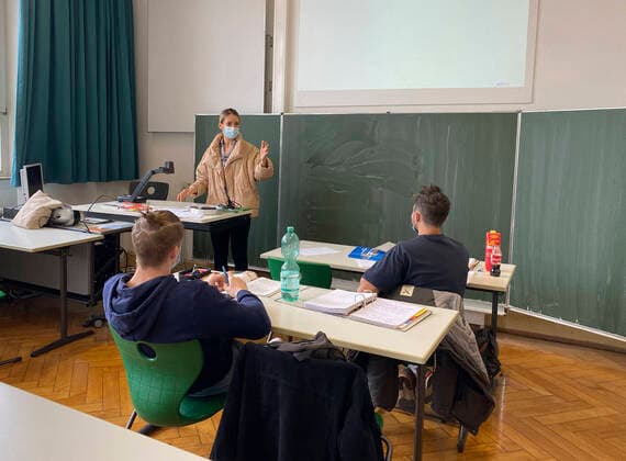 Teacher with thick winter jacket and face mask in classroom teaching, gestures, corona crisis, Stuttgart, Baden Württemberg, Germany Coronavirus