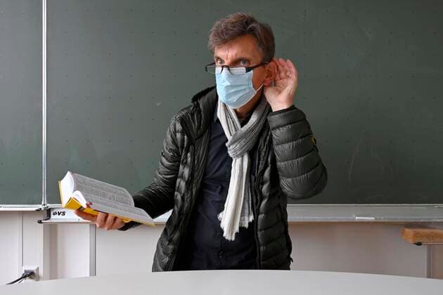 Teacher with thick winter jacket, scarf and face mask in class, hand on ear, communication problems, corona crisis, Stuttgart, Baden Württemberg, Germany, Europe Copyright: imageBROKER/MichaelxWeber iblimw05902325.jpg