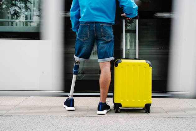 Creative Highlights Symbolfotos Young man with artificial limb and foot standing by luggage at railroad station model released Symbolfoto JCZF00323