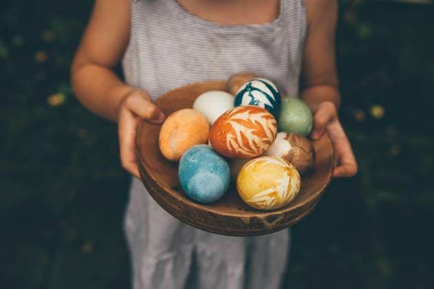 Baby girl holding bowl of colorful organically colored Easter eggs model released Symbolfoto MBEF01464