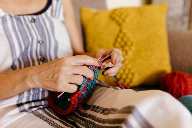 Mature woman knitting while sitting on sofa at home model released Symbolfoto TCEF01193