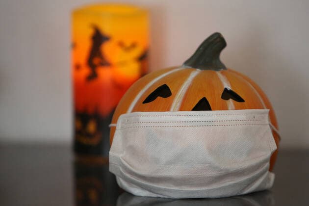 Symbolic image on the subject of Halloween in times of the Corona pandemic, a porcelain pumpkin head with mouth guard, behind it a candle, lamp Symbolic image, Halloween, Corona on 27 10 2020 in Siegen Germany