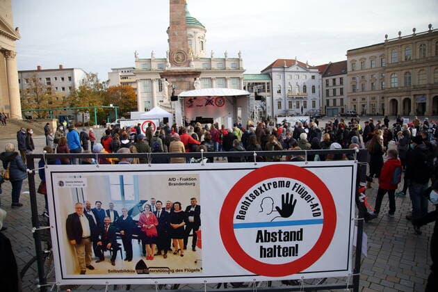 Concert visitors and a banner with a group photo of the AfD faction and the inscription Right-wing extremist wing AfD keep distance at a protest concert against the election of the new AfD faction leader on the Alter Markt at the Brandenburg Parliament in Potsdam, 27 October 2020 Protest concert Flügel statt Flügel in Potsdam