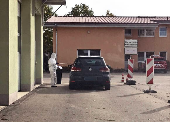30 10 2020, Corona Test Station in Mindelheim at the district building yard An employee in a full-body protective suit hands a car driver the test stick through the open window 30 10 2020, Corona Test Station Mindelheim 30 10 2020, Corona Test Station Mindelheim