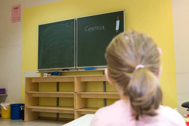 Child in a classroom of a primary school with the word Corona