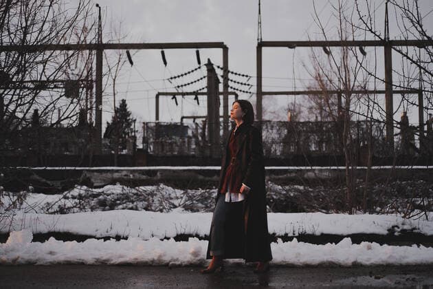 IMAGO Creative: Jahreszeit Winter, Spaziergang Woman in leather coat walks in industrial area in winter, low ke CR_AXHBBX201027B-539972-01 ,model released, Symbolfoto