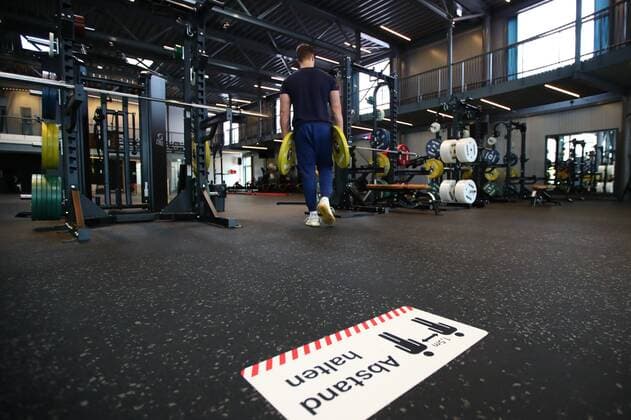 Diez gyms in the Corona time note keep distance on the floor of a gym, behind it a man with weight plates gyms in the Corona time Copyright: xEibner-Pressefotox EP_RWS