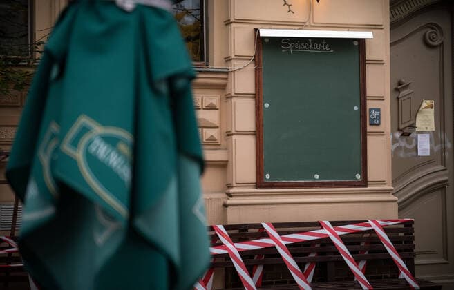 A barrier tape over seats in front of a gastronomy business with empty menu in Berlin Prenzlauer Berg photo picture enclosure gastronomy in the lockdown