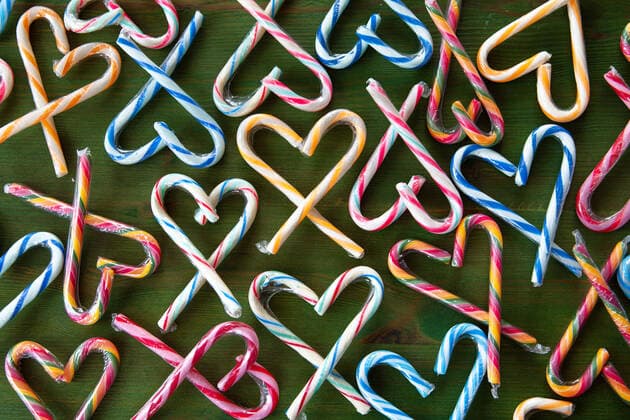 Bunte Zuckerstangen in Herzen arrangiert auf grünem Hintergrund *** Colorful candy canes in hearts arranged on a green background 1079706386