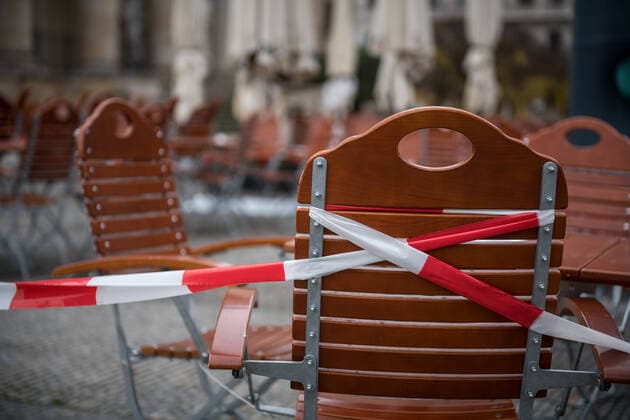 A barrier tape over chairs and tables in front of a catering trade enterprise at the Gendarmenmarkt in Berlin Mitte Photo picture enclosure catering trade in the Lockdown