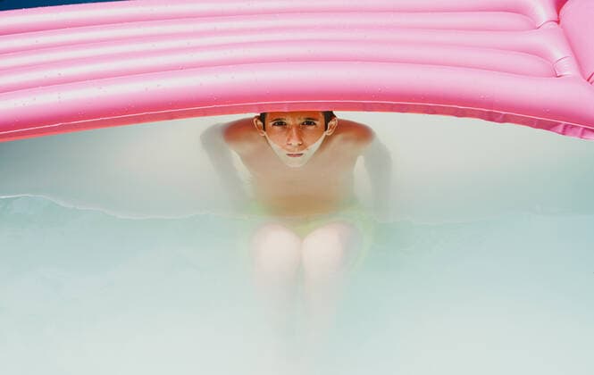 IMAGO Creative: 2021 Favoriten IMAGO Creative: Kraft des Wassers Boy in a pool taking a bath under a pink flat looking at camera. Zaragoza, Aragon, Spain CR_RUBO201207B-575453-01 ,model released, Symbolfoto