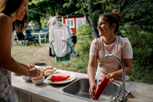 Smiling daughter and mother talking while preparing food in yard during summer, MA82694, Sweden, Stockholm Archipelago, model released, property released Copyright: xMaskotx