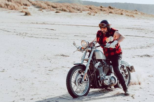 Adult man riding motorcycle on empty sandy beach of ocean, Model released Copyright: xAlbertoxMenendezx MR
