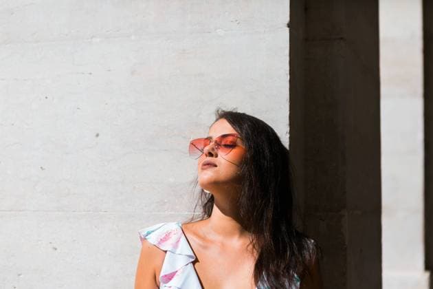 Peaceful gorgeous woman in trendy outfit and shiny sunglasses standing on white wall on scenic street, Model released Copyright: xAlexandraxCoelhox MR