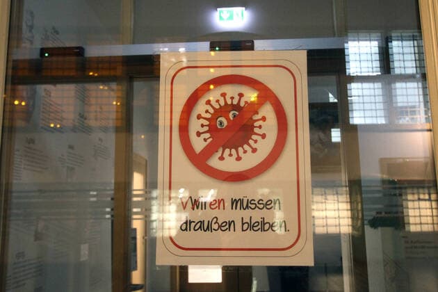 Pictogram with crossed out Corona Virus and writing we viruses have to stay outside stuck on the entrance door to a closed shop in the city centre of Frankfurt, Hesse, Germany