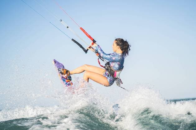 Side view of fit female kite surfer in swimsuit ridding waves in sea on sunny day in summer Copyright: xAlvaroxMonterox Model Released